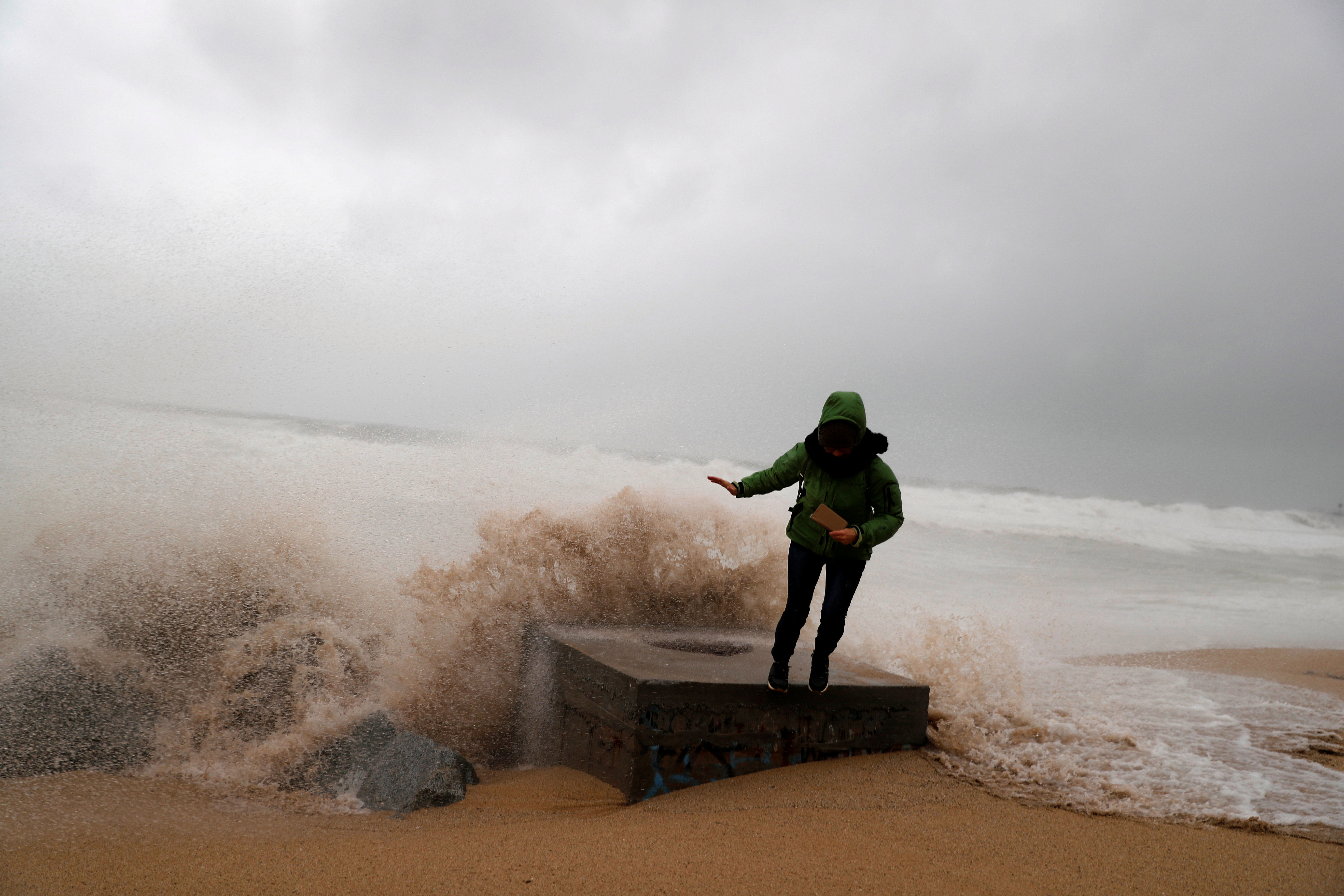 A woman is pictured braving the storm in Badalona, near Barcelona